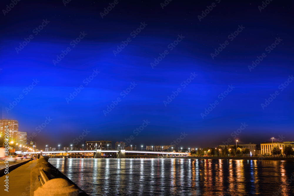 Starry sky over the city by the river and the bridge.