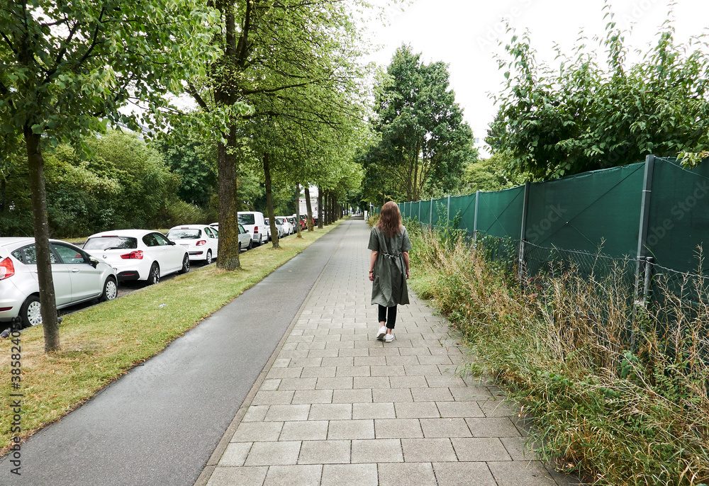 a girl in the summer walks on the sidewalk in Munich