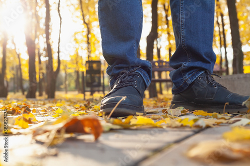 Legs of man in autumn park among fallen leaves