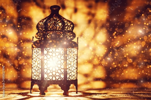 Arabic lantern with burning candle glowing and golden bokeh