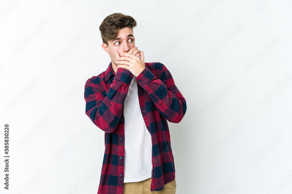 Young caucasian man isolated on white background thoughtful looking to a copy space covering mouth with hand.