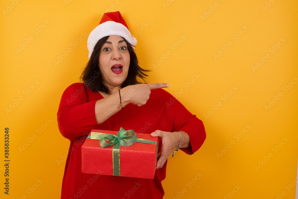 Look over there! Beautiful blonde caucasian woman pointing away and smiling to you while standing against grey background. Look over there! Beautiful blonde caucasian woman pointing away and smiling to you while standing against grey background.