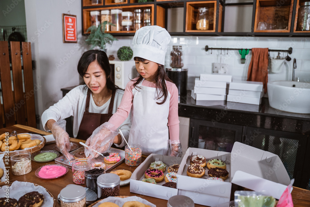 Mother and daughter having fun in the kitchen while to making donuts together Mother and daughter having fun in the kitchen while to making donuts together