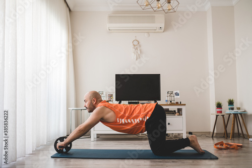 Obraz na płótnie Young man doing sports on the mat by himself at home, doing fitness for a healthy life