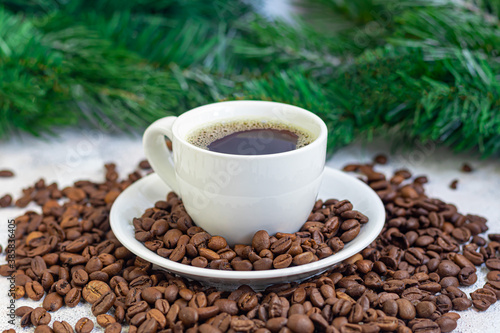 A cup of delicious aromatic coffee. It is placed on a substrate made of coffee beans. New Year holiday concept. On a light background.