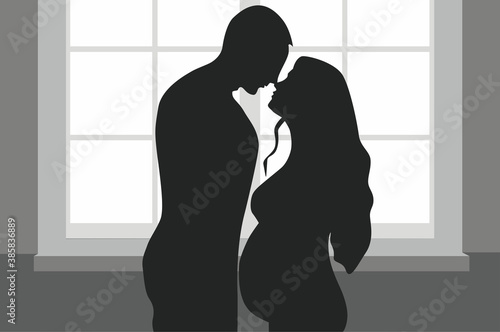 silhouette of a person in a window. Pregnant woman and man. Family couple waiting for a baby