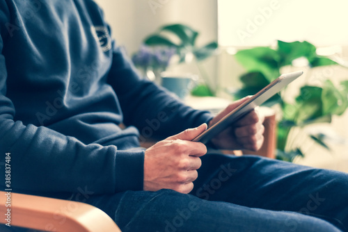 A man uses a wireless tablet device at home to check email and social media messages