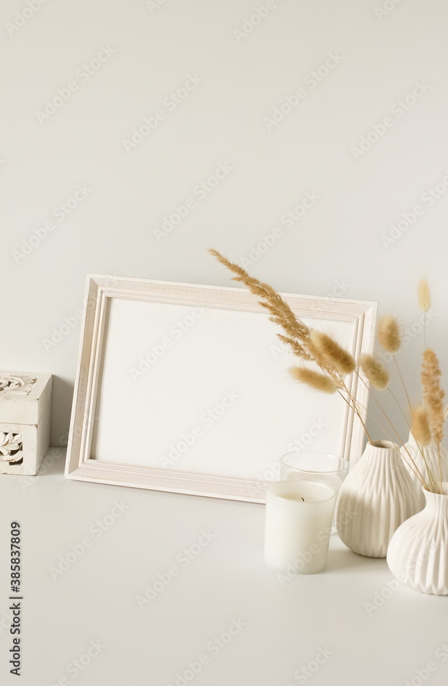 Photo frame mock up, fluffy reeds bouquet in a vase, interiour accessories near the white wall. Copy space template. Minimalist scandinavian interior design . Photo frame mock up, fluffy reeds bouquet in a vase, interiour accessories near the white wall. Copy space template. Minimalist scandinavian interior design .