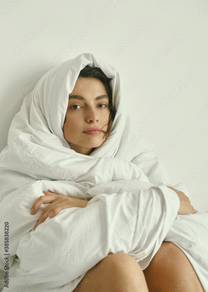 Portrait of young beautiful girl with blanket on white background. At home. Comfort. Healthy lifestyle, clear skin. Curly hair. Emotions. About sleeping and awakening. Portrait of young beautiful girl with blanket on white background. At home. Comfort. Healthy lifestyle, clear skin. Curly hair. Emotions. About sleeping and awakening.
