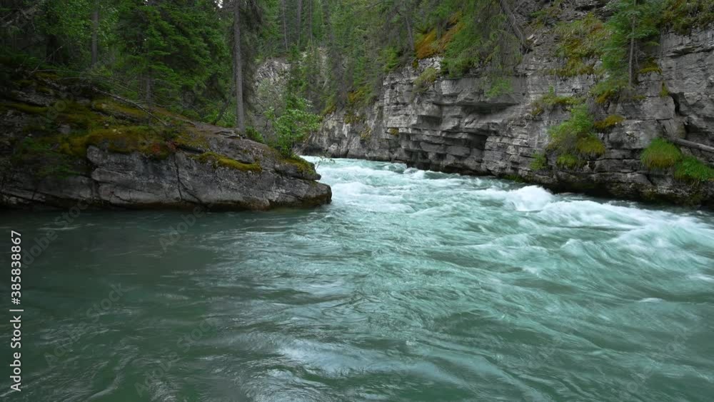 Fast flowing green colored mountain stream flowing between large rock outcrops with green spruce trees and grass clinging to the cliff.
Fast flowing green colored mountain stream flowing between large rock outcrops with green spruce trees and grass clinging to the cliff.