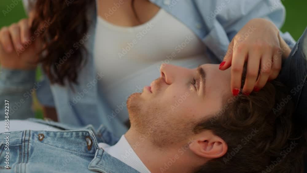 Brunette girl stroking guy hair outdoors. Man and woman lying on the ground Brunette girl stroking guy hair outdoors. Man and woman lying on the ground