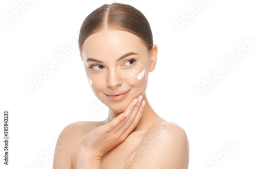 Portrait of young beautiful brown-eyed woman with face cream on cheekbones isolated on white background, skin care concept