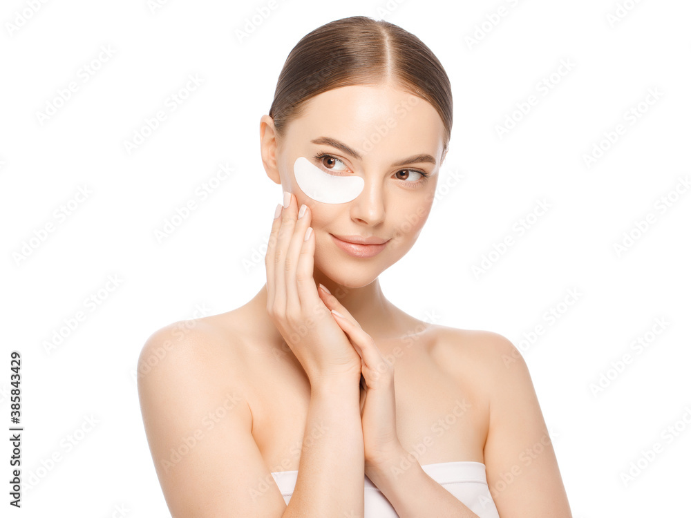 Young beautiful woman applying eye patch, touching her face with fingers, looking away, isolated on white background. Female skin care concept Young beautiful woman applying eye patch, touching her face with fingers, looking away, isolated on white background. Female skin care concept