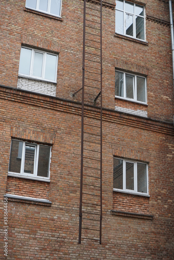A fire escape on a brick building with white modern windows.