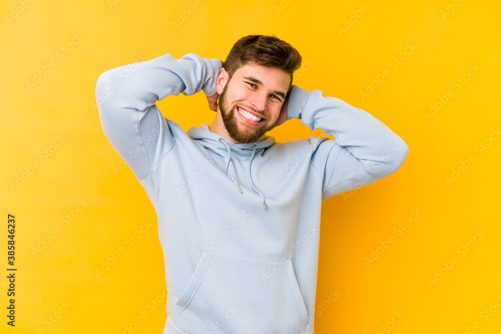 Young caucasian man isolated on yellow background stretching arms, relaxed position. Young caucasian man isolated on yellow background stretching arms, relaxed position.