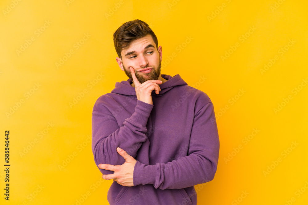 Young caucasian man isolated on yellow background contemplating, planning a strategy, thinking about the way of a business. Young caucasian man isolated on yellow background contemplating, planning a strategy, thinking about the way of a business.
