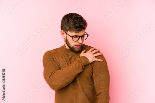 Young caucasian man isolated on pink background having a shoulder pain. © Asier