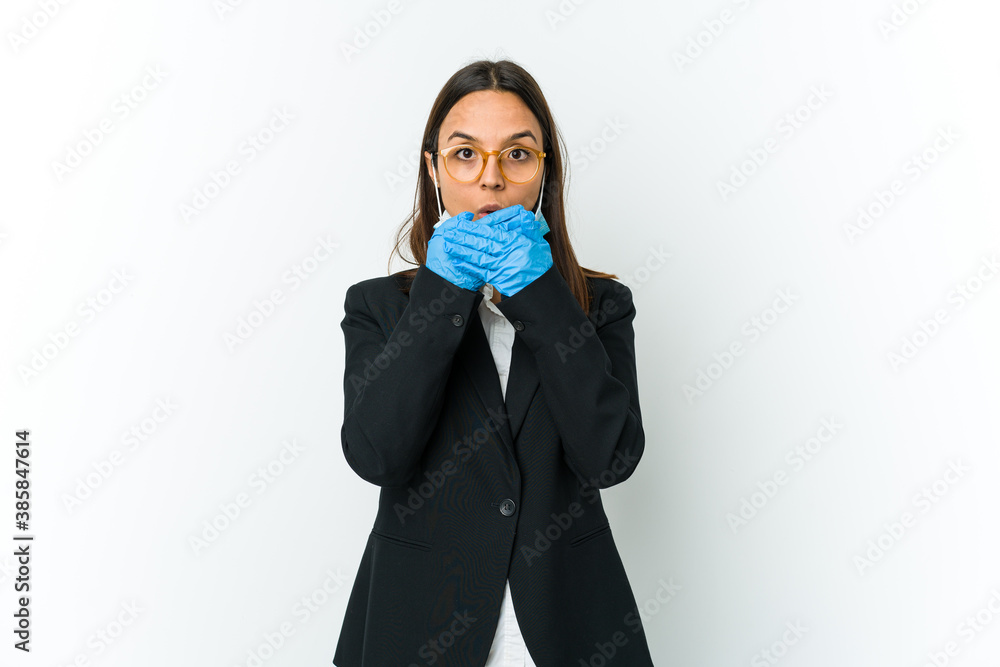 Young business latin woman wearing a mask to protect from covid isolated on white background shocked covering mouth with hands. Young business latin woman wearing a mask to protect from covid isolated on white background shocked covering mouth with hands.