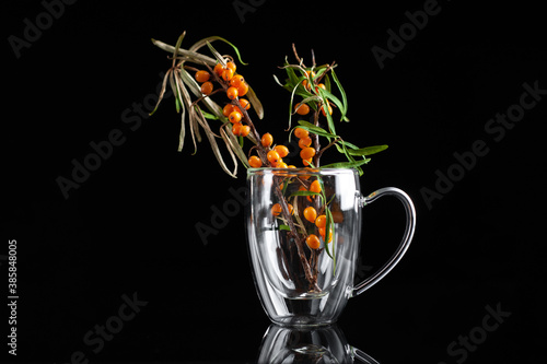 Fototapeta Naklejka Na Ścianę i Meble -  sandthorn berries in a transparent mug on a black background