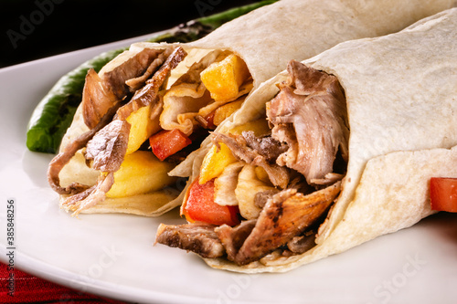 Photography A delicious doner donair kebab wrap with spicy meat, lettuce, tomato, red onion and sauce