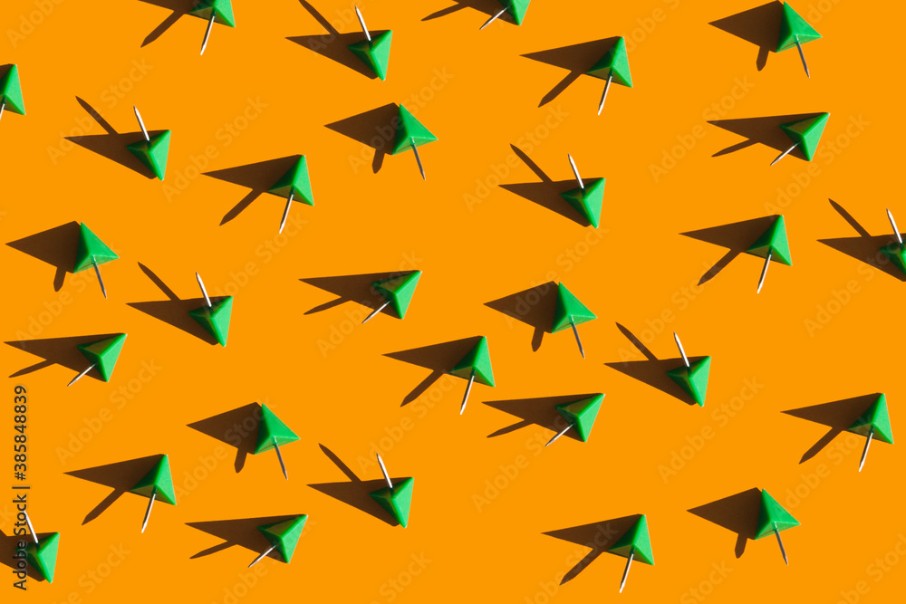 green push pins on a bright orange background. School and office supplies top view. Colorful background green push pins on a bright orange background. School and office supplies top view. Colorful background
