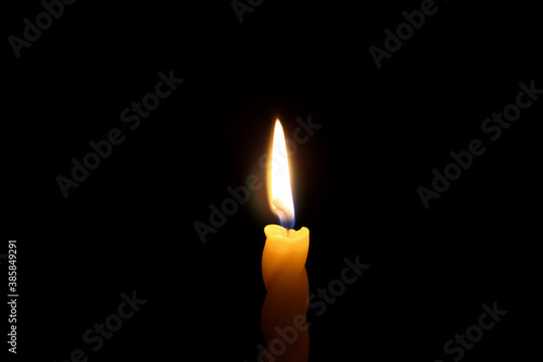 Flame of a single candle on a dark background.