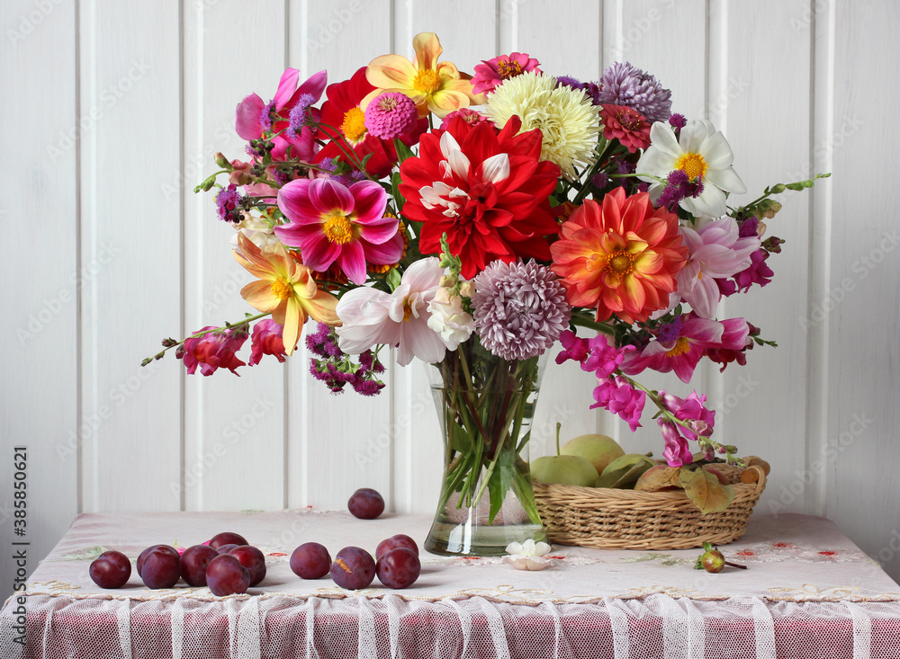 Φωτογραφία bouquet of garden flowers in a glass vase, plums and apples.