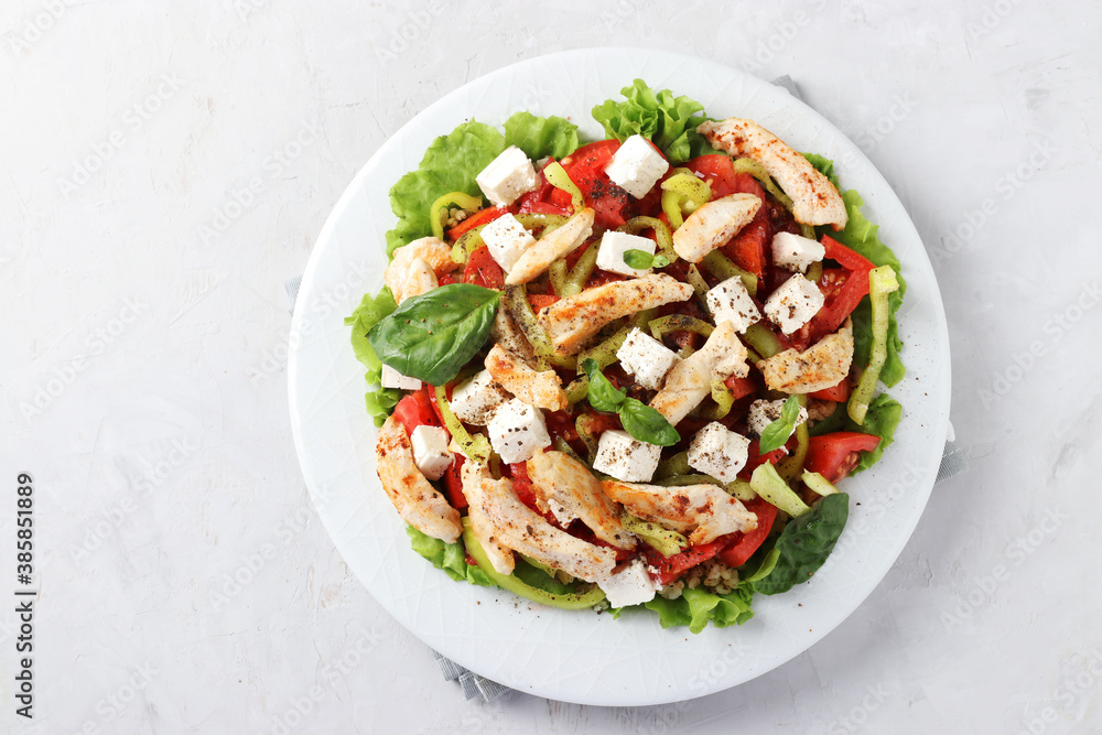 Salad with bulgur, baked chicken, bell pepper, basil and feta on a white plate, view from above Salad with bulgur, baked chicken, bell pepper, basil and feta on a white plate, view from above