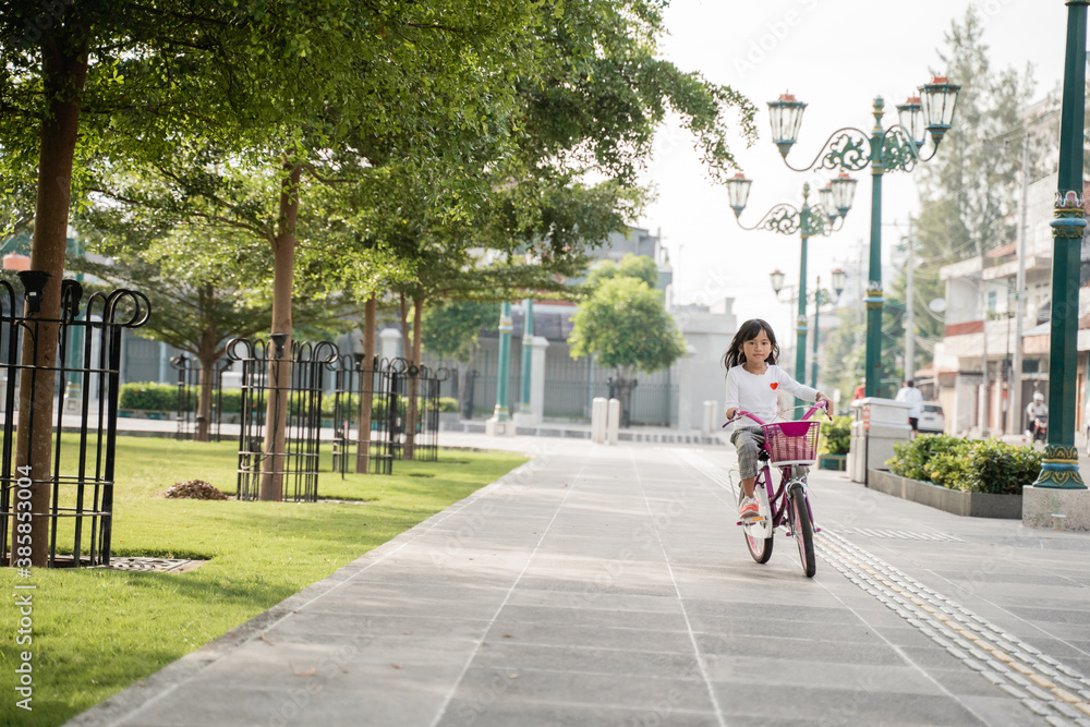 Φωτογραφία a portrait of a cheerful and happy little girl playing a bicycle in the park whe