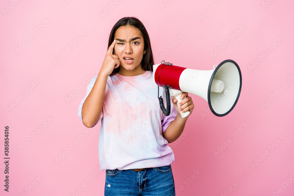 Young asian woman holding a megaphone isolated on pink background showing a disappointment gesture with forefinger. Young asian woman holding a megaphone isolated on pink background showing a disappointment gesture with forefinger.