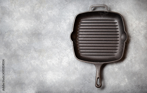 Black iron empty grill pan on gray concrette background. top view photo