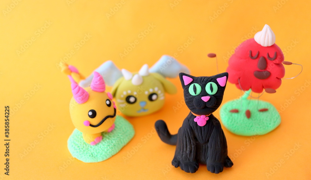 Funny crafts made of air plasticine of different shapes, selective focus on an orange background, close-up made by children's hands. Funny crafts made of air plasticine of different shapes, selective focus on an orange background, close-up made by children's hands.