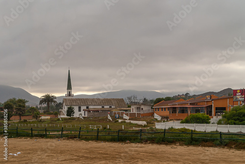 Coquimbo, Chile - December 7, 2008: Early morning overcast brown cloudscape. White Capilla San Gabriel chapel with spire and red houses nearby along coastal way to La Serena.