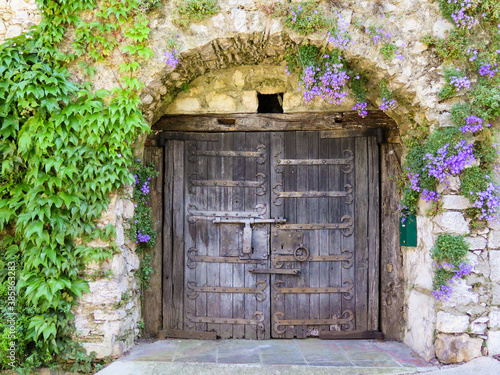 Old wooden doors of an old stone house covered by purple flowers in the typical village of La Turbie in provence  photo