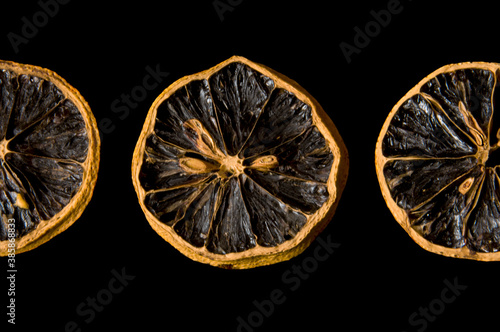 Three dry lemon wedges on black isolated background close up