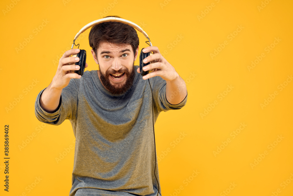 Fototapeta premium Man in headphones listens to music technology lifestyle fun people yellow background