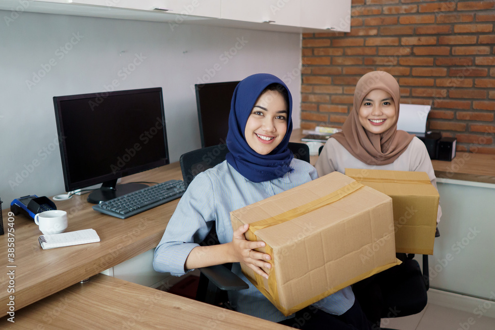 attractive cheerful young muslim business woman working on laptop and smiling while sitting at her desk modern office with her friend at studio attractive cheerful young muslim business woman working on laptop and smiling while sitting at her desk modern office with her friend at studio
