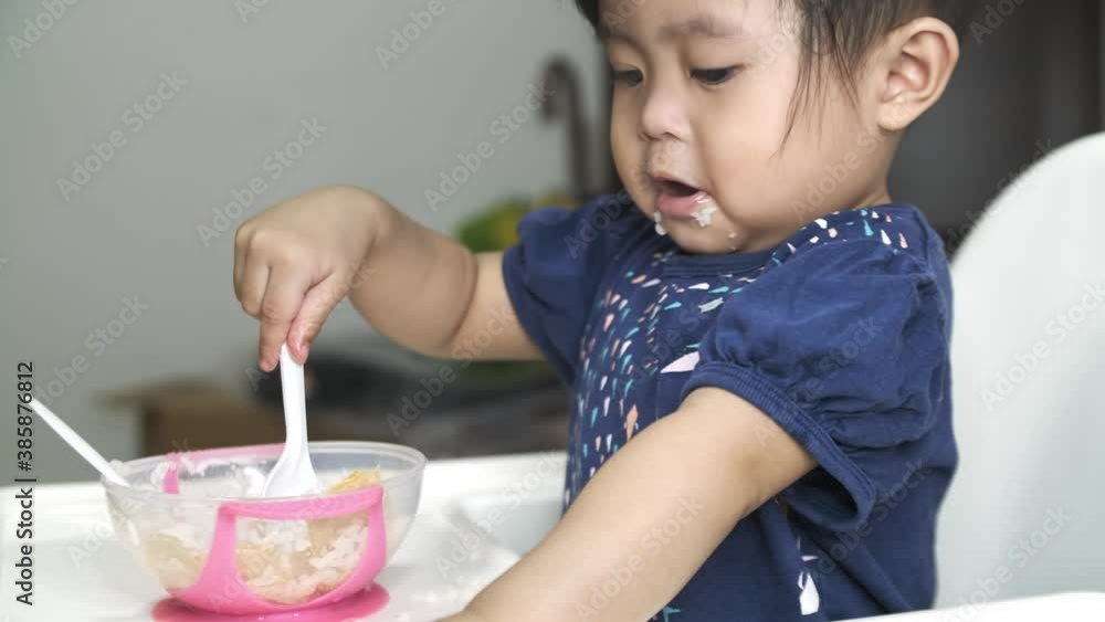 Cute asian little baby eating puree of bowl during daytime. Cute asian little baby eating puree of bowl during daytime.