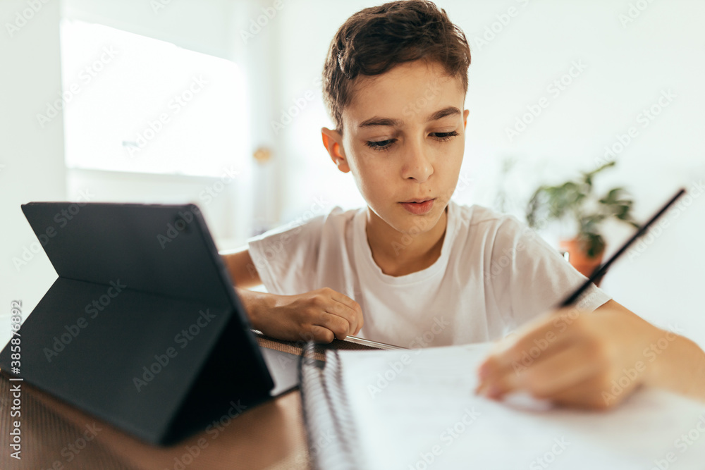 Education and technology concept - student boy with tablet computer learning at home Education and technology concept - student boy with tablet computer learning at home