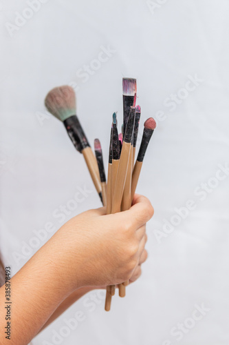 child's hand holding makeup brushes.