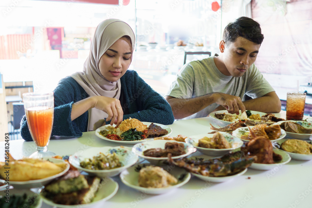 portrait of the couple young eating dish padang food