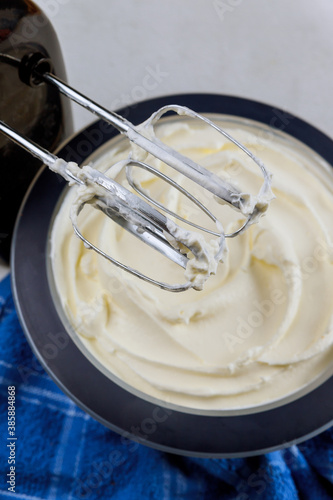 White cream for cake in bowl and mixer.