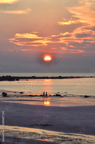 Photography Colorful sky and sunset over Cape Cod Bay with unrecognizable couple (in silhouette) walking along beach in East Dennis, Massachusetts, casting their reflections on wet sand