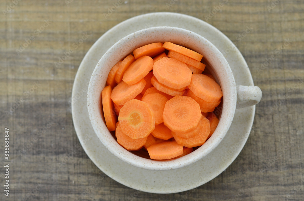 Cup with slices carrots on wooden table, closeup Cup with slices carrots on wooden table, closeup