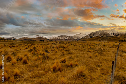 Fotografie High country South Island farm land with tussock covered terrain at the base of