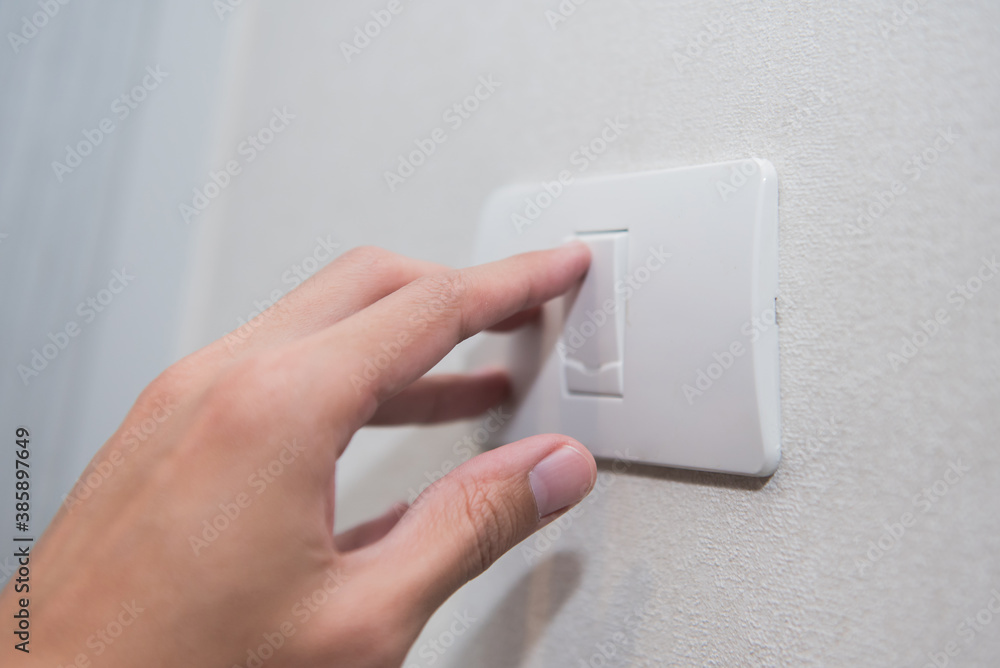 Unidentified man hand with finger on light switch turn on turn off lights on white wall. Unidentified man hand with finger on light switch turn on turn off lights on white wall.