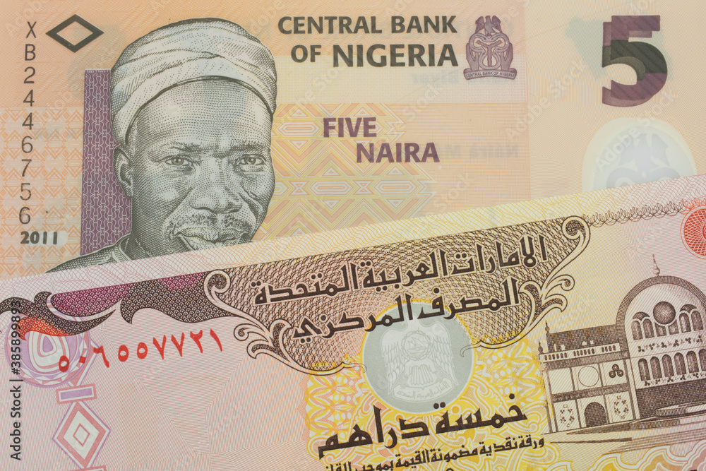 Fototapeta premium A macro image of a orange, plastic five naira note from Nigeria paired up with a colorful five dinar bank note from the United Arab Emirates. Shot close up in macro.
