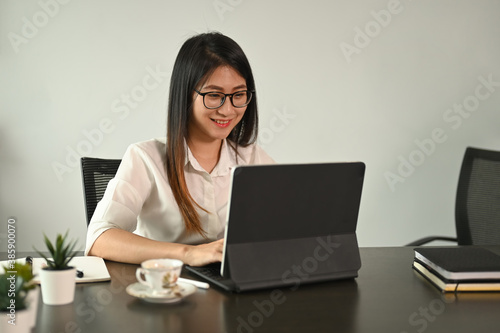 Young female fleelance using computer tablet on black wooden table.