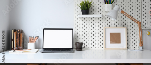 Mockup blank screen laptop and office supplies on white desk. photo