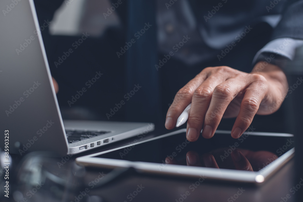 Businessman hand using on digital tablet touching on screen and working on laptop computer in office Businessman hand using on digital tablet touching on screen and working on laptop computer in office